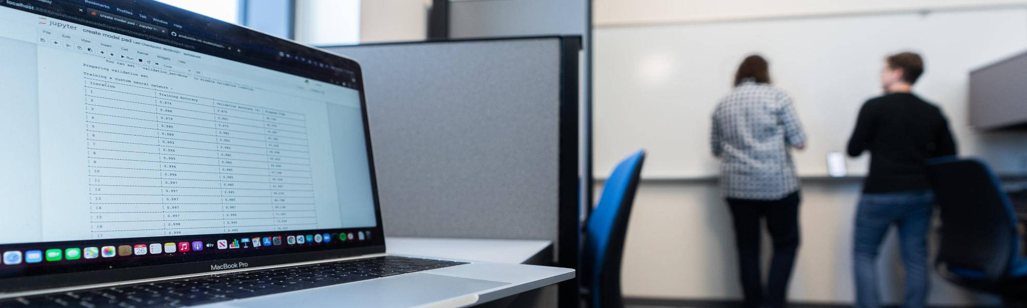 Picture of a MacBook and students working